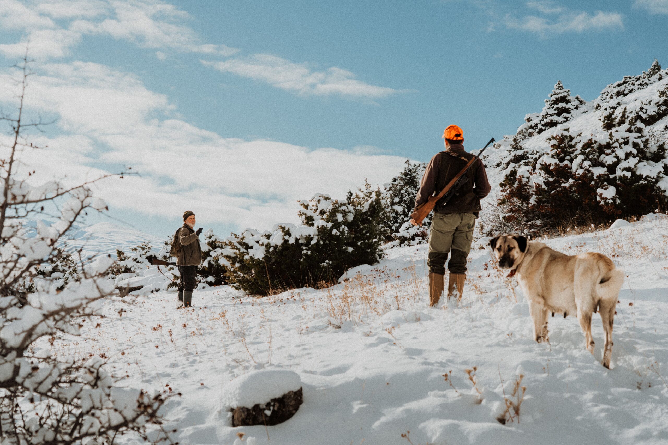 Zwei Jäger mit Hund im Schnee